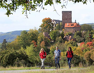 Wanderer bei Werbach vor der Gamburg: Gerade jetzt im Herbst bietet das „Liebliche Taubertal“ naturnahes Wandern. Die Natur legt ihr buntes Herbstkleid an, und die Weinlese ist im Gange. Foto: TLT/Peter Frischmuth