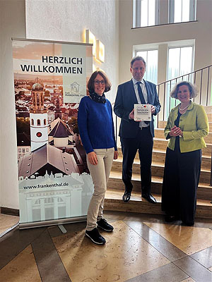 Dr. Dörte Kaufmann, Leiterin des Stadtarchivs, Oberbürgermeister Martin Hebich mit der Plakette „Ort der Demokratiegeschichte“ und Dr. Maria Lucia Weigel, Leiterin des Erkenbert-Museums